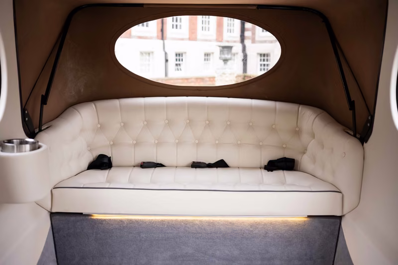 Century Imperial ivory button-tufted rear bench above grey carpet, with warm lighting beneath the seat.